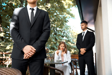 Young businesswoman with bodyguards in cafe