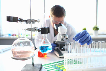 Portrait of a young chemist looking in binocular microscope looking for pathology analyzes patient at medical hospital for treatment disease tumors