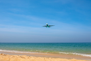 Fototapeta na wymiar The plane comes in for landing flying over a beautiful tropical beach with fine sand and blue sea.