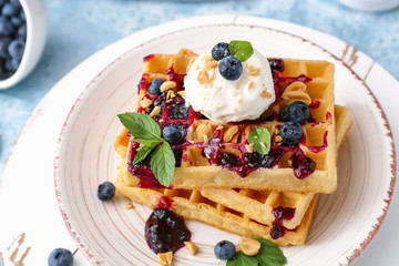 Tasty waffles, ice cream and blueberries on plate