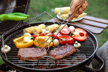 Man cooking food on barbecue grill outdoors, closeup