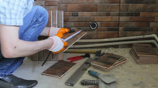 measure the ceramic tile,a man measures the remains of a ceramic tile with a tape measure