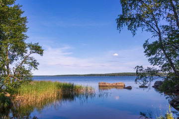 Fototapeta na wymiar Landscape with lake and blue sky. Quiet Monrepos park in Vyborg, Russia..