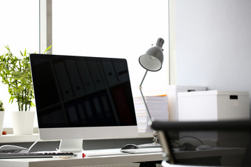 Fashionable modern stylish silver computer stands in office on table against window