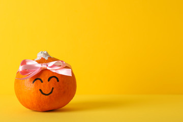 Happy pumpkin with bow on yellow background, space for text