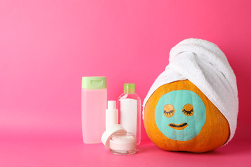Funny pumpkin and skin care accessories on pink background, space for text