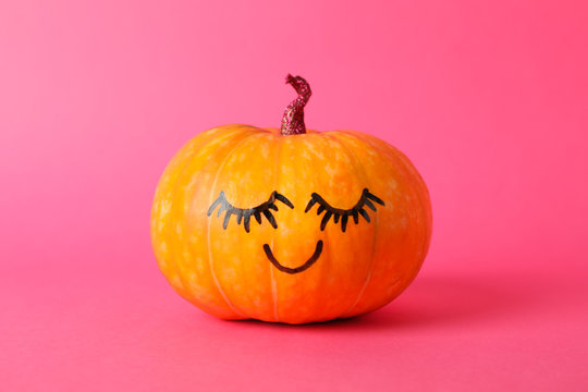 Pumpkin with smile on pink background, space for text