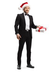Young elegant man wearing a santa claus hat and holding a gift box
