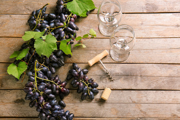 Sweet grapes with wineglasses corkscrew on wooden table