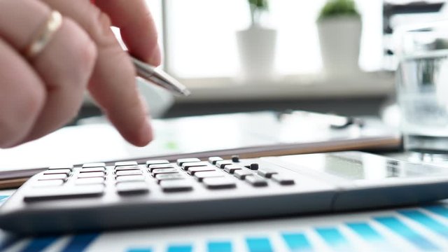 Silver calculator with gray keyboard is lying on desk graph and pen office setting. Calculation of family expenses social income population freelance irs situation growth research concept