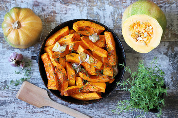 Pumpkin slices with thyme and garlic in a pan. Healthy autumn food. Vegan lunch.