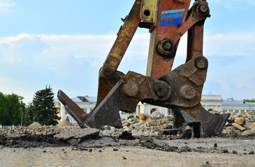 Excavator with hydraulic shears breaks asphalt on a construction site. Hydraulic shear crusher pulverizer for excavator. Heavy-duty mechanical concrete crusher. Attachments Equipment - Image