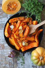 Pumpkin slices with thyme and garlic in a pan. Healthy autumn food. Vegan lunch.
