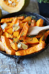 Pumpkin slices with thyme and garlic in a pan. Healthy autumn food. Vegan lunch.