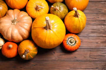Many fresh raw whole pumpkins on wooden background, flat lay. Holiday decoration