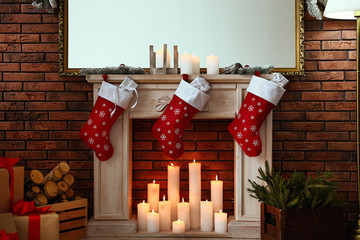 Decorative fireplace with Christmas stocking and gifts in stylish room interior