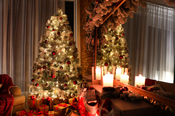 Stylish room interior with beautiful Christmas tree and gifts at night
