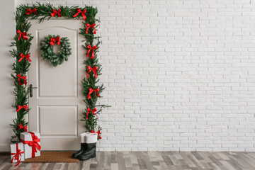 Stylish hallway interior with decorated door and Christmas gifts, space for text