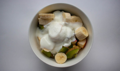 Fresh tasty fruit salad with yogurt on white background