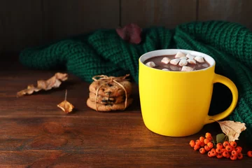 Zelfklevend Fotobehang Cup of hot drink and knitted sweater on wooden table, space for text. Cozy autumn atmosphere © New Africa