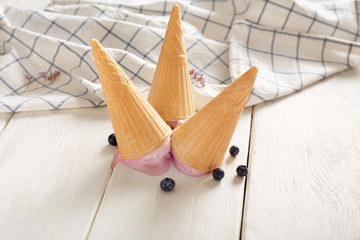 Wafer cones with tasty blueberry ice cream on white table