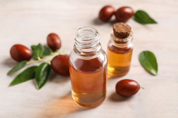 Glass bottles with jojoba oil and seeds on light table