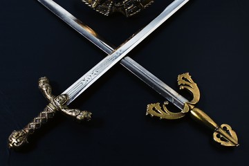 two crossed knightly swords on a black background