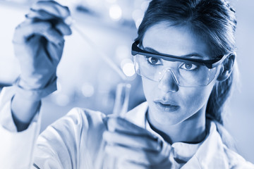 Life scientists researching in laboratory. Focused female life science professional pipetting...