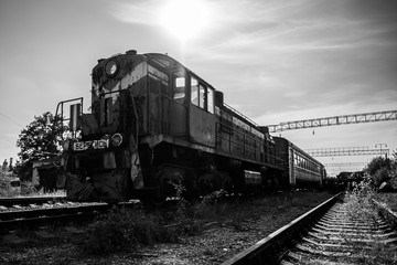 Fototapeta na wymiar Black and white rusty train on abanxdoned railway line