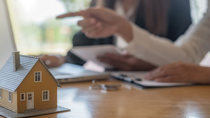 House model with agent and customer discussing for contract to buy, get insurance or loan real estate or property background.