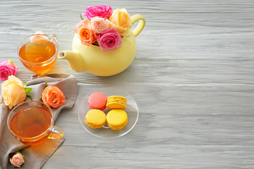 Beautiful rose flowers with tea and dessert on grey table