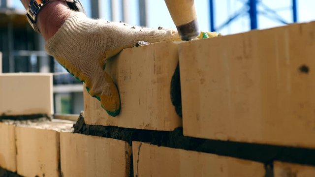 Bricklayer doing brickwork at a construction site. A bricklayer works at a site, using trowel.