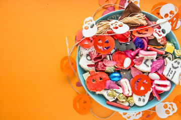 Halloween Jack o Lantern candy bowl with candy and halloween cookies Trick or Treat on orange background