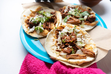 Mexican birria tacos with onion and cilantro on white background