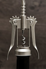 metal corkscrew on the neck of a bottle of wine against a dark background