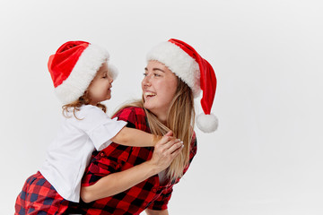 Christmas time. Happy hugging family, mother and daughter, little child playing in Santa hats, isolated on white. New year holiday concept