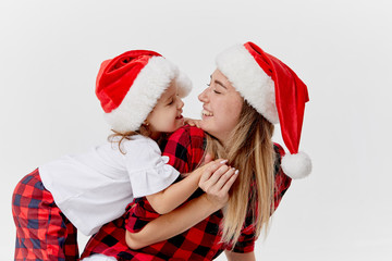 Christmas time. Happy hugging family, mother and daughter, little child playing in Santa hats, isolated on white. New year holiday concept