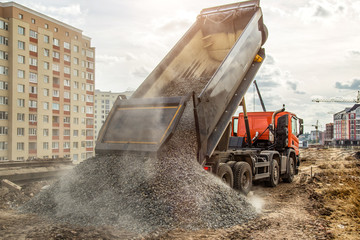 Construction truck tipping dumping gravel on road construction site,tip truck and ripper at work...