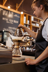 Professional barista preparing coffee using chemex pour over coffee maker and drip kettle. Young...