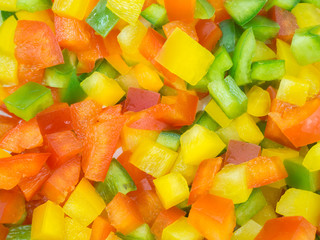 Red, green and yellow sweet bell peppers chopped on white background