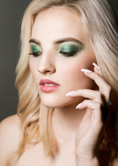 Fototapeta premium Sexy beauty face. Glamour portrait of beautiful woman model with evening makeup. Fashion shiny highlighter on skin, sexy lips make-up and perfect eyebrows. Green eye shadow.