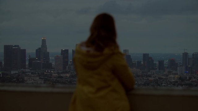 Back view of Caucasian female enjoying the view of of Los Angeles Downtown from Griffith observatory, all brand names and logos removed. 4K UHD