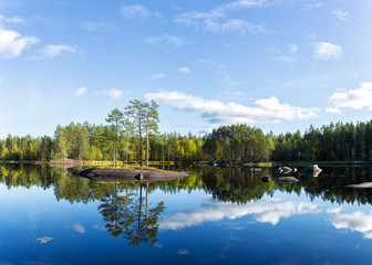 Landscape with the island on the lake and blue sky. Forest and beautiful blue sky with white clouds and reflection on the lake water.