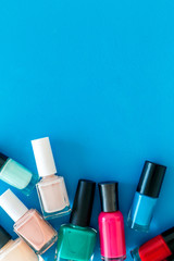 Obraz premium Choose nail polish. Polish bottels on blue background top view copy space