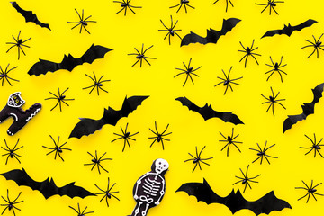 Cute Halloween decoration. Bats, spiders and special cookies on yellow background top view pattern