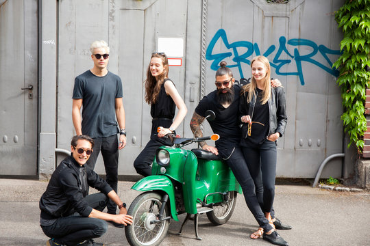 Group of five black dressed friends with green moped