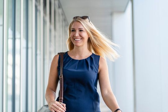 Portrait of smiling blond businesswoman wearing blue summer dress
