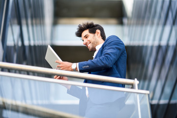 Smiling businessman using tablet on balcony of an office building