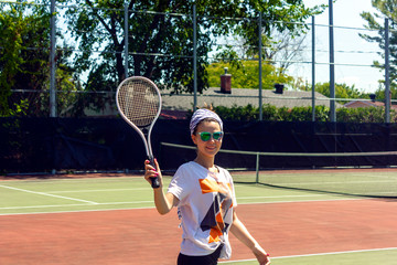 girl, young woman plays tennis smiles in camera on a coart in Gatineau, Quebec, Canada during the summer