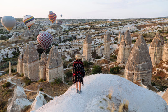 Young woman and hot air balloons in the evening, Goreme, Cappadocia, Turkey